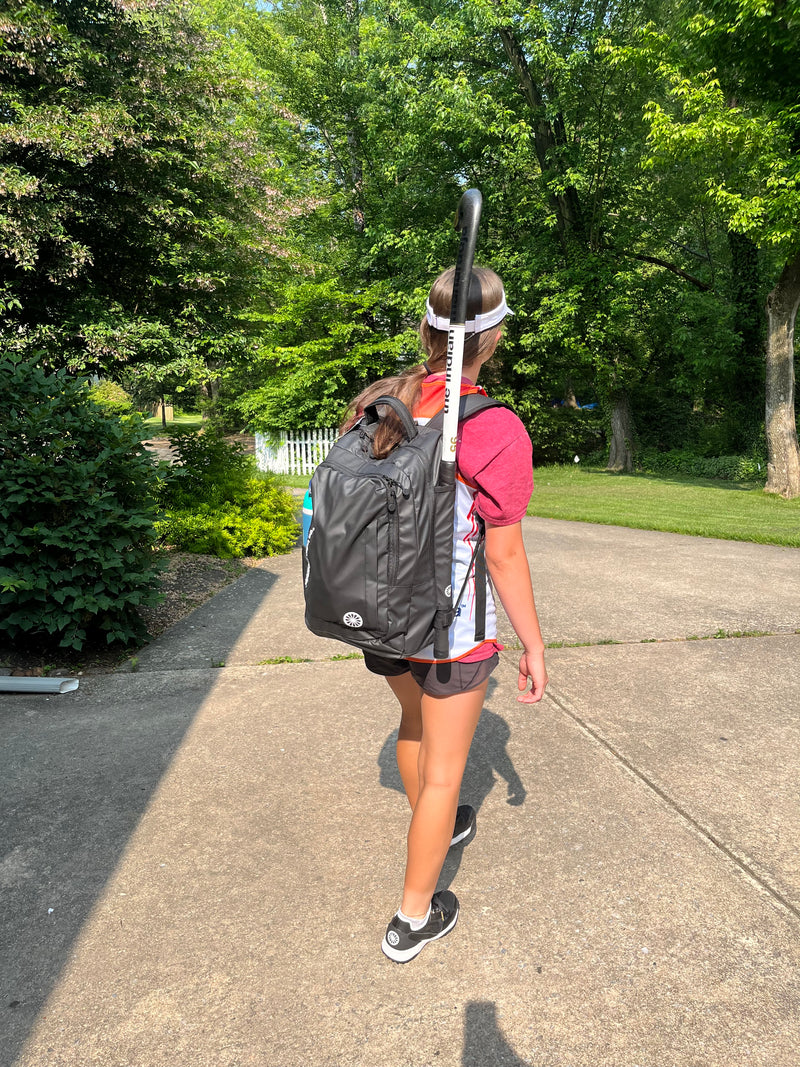 Model wearing All sports backpack PMC black with stick holder on the way to practice!